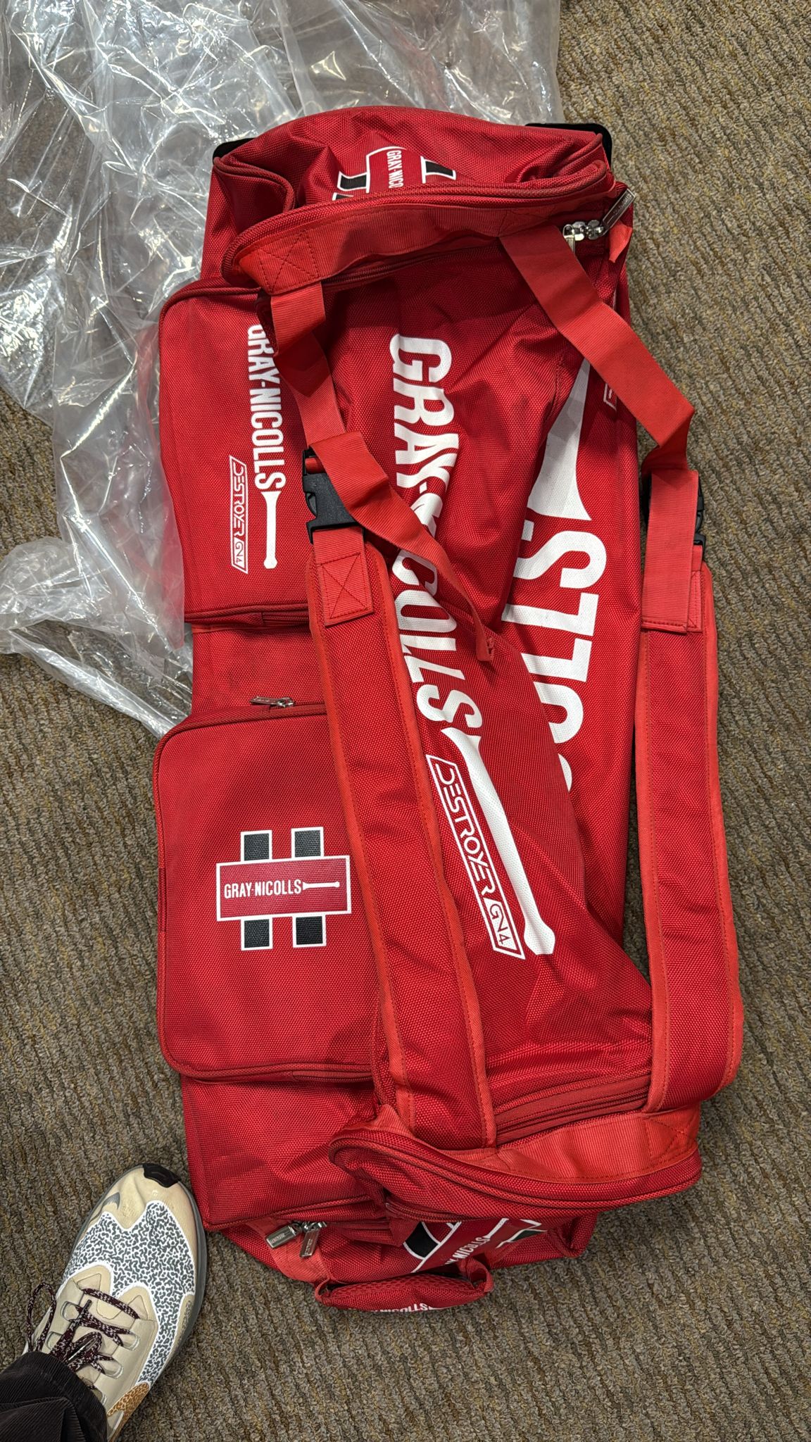 Red sports bag with visible branding on a carpeted floor