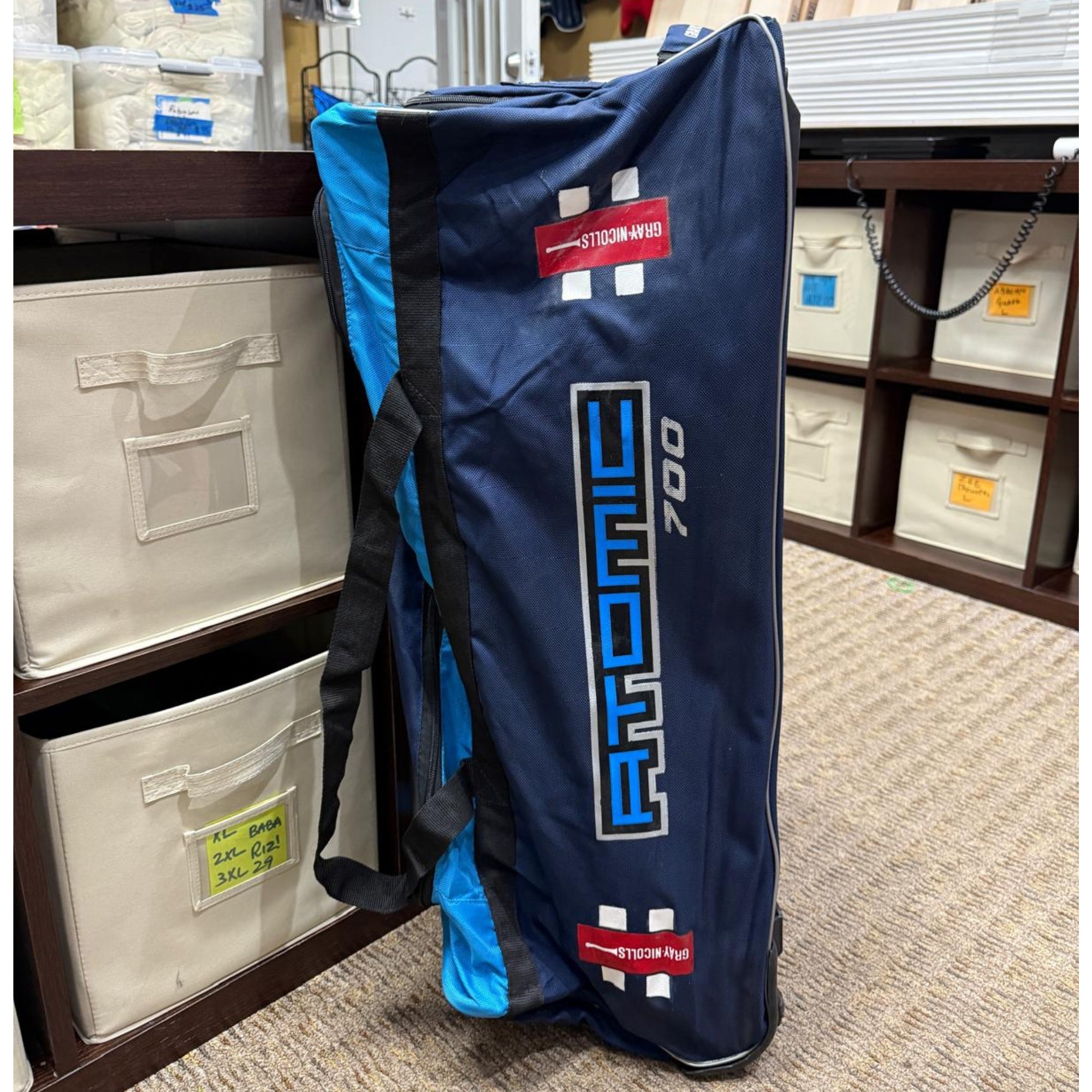 Blue and black bag with Gray nicolls logo on a shelf in a store
