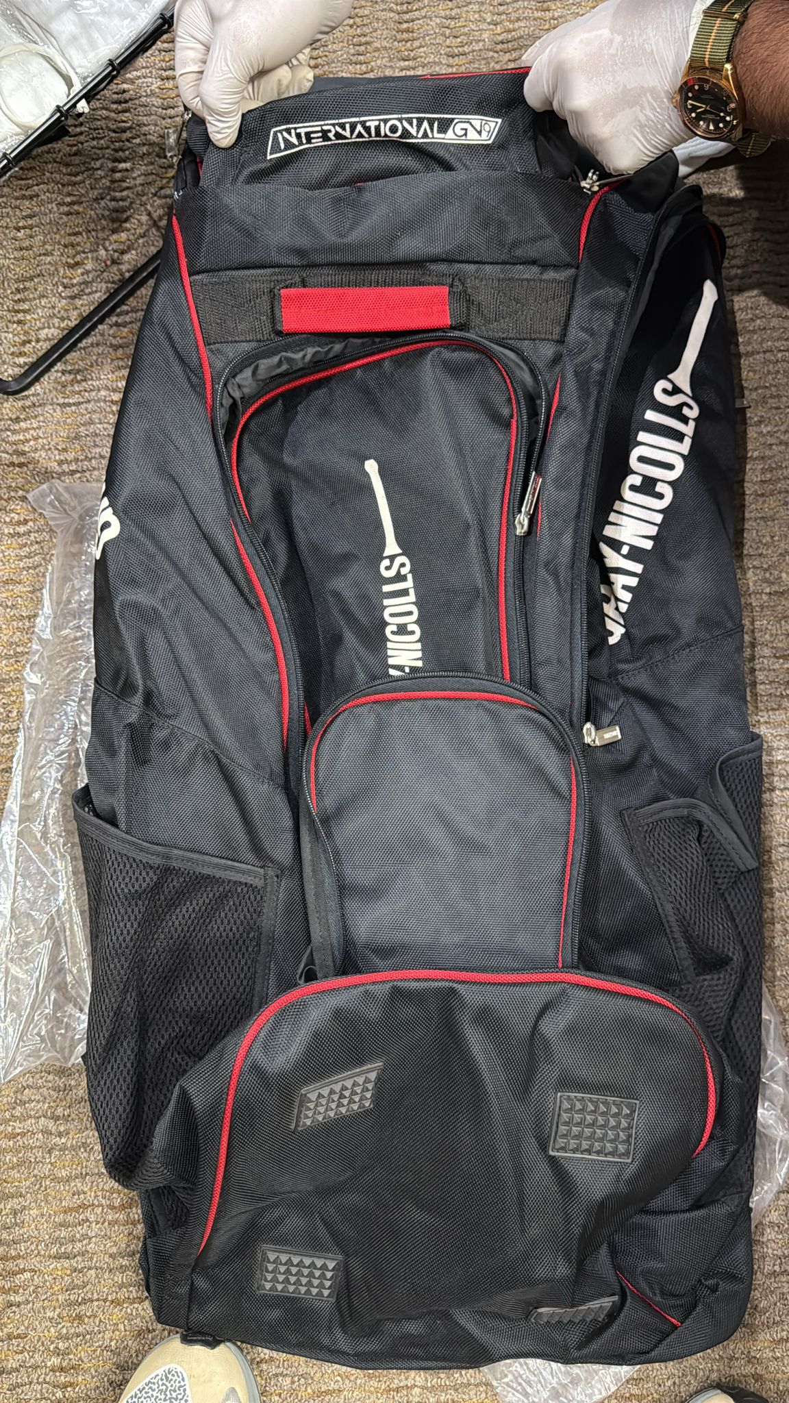Black sports bag with red accents and 'International Sports' branding on a brown surface.