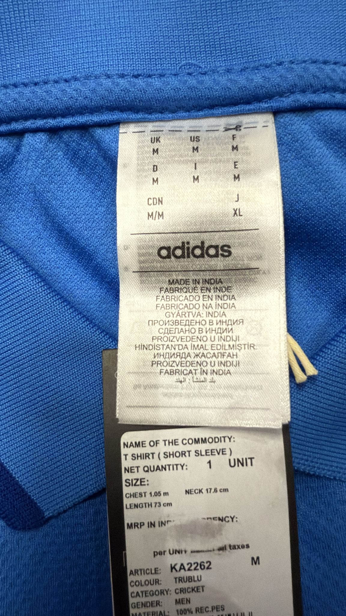 Adidas label on a blue garment with size and material information.